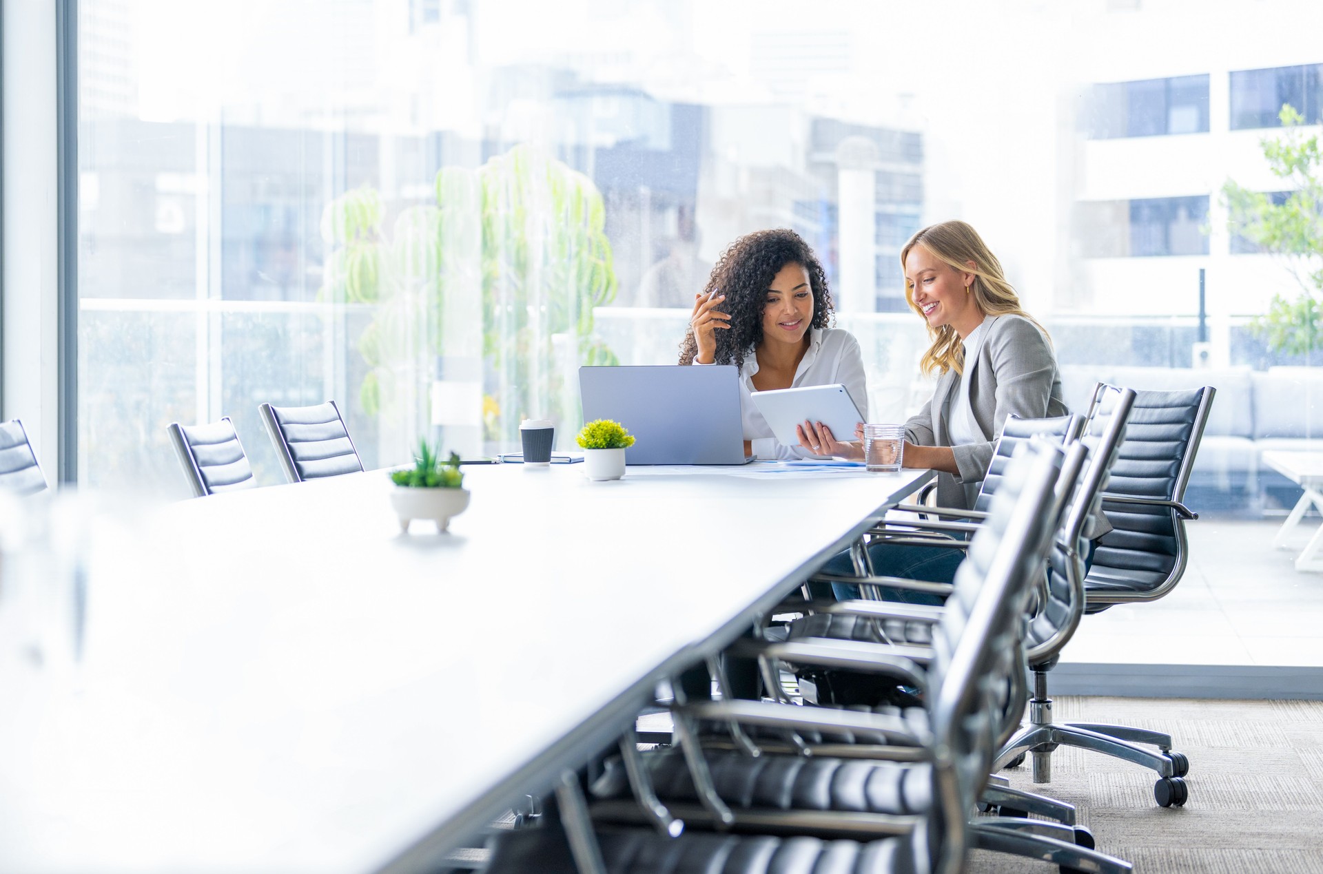 Business colleagues having a conversation in a board room. They are both young business people casually dressed in a modern office. Business colleagues having a conversation in a board room. They are both young business people casually dressed in a modern office.